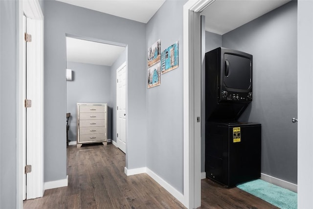 corridor featuring baseboards, dark wood-type flooring, and stacked washer and clothes dryer