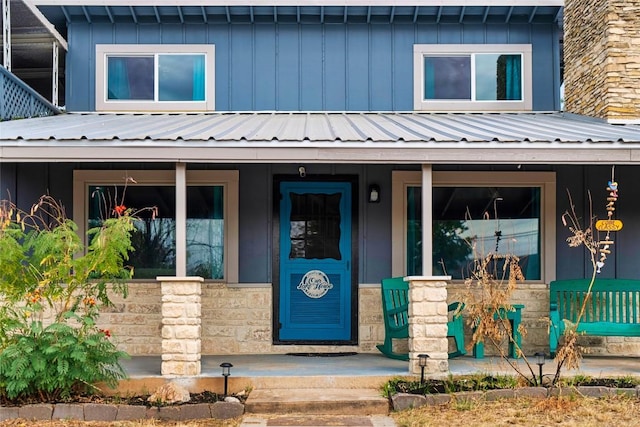 view of front of house with covered porch, stone siding, metal roof, and board and batten siding