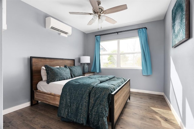 bedroom featuring ceiling fan, baseboards, an AC wall unit, and wood finished floors