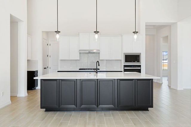 1832 Camay St, Leander, TX 78641 - kitchen with wall oven, stainless steel microwave, under cabinet range hood, tasteful backsplash, and white cabinetry
