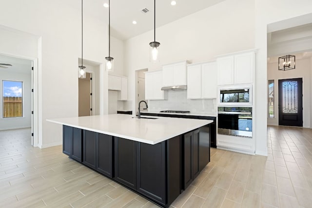 1832 Camay St, Leander, TX 78641 - kitchen featuring oven, built in microwave, a towering ceiling, white cabinetry, and gas cooktop