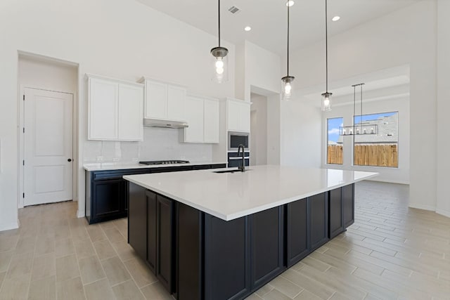 1832 Camay St, Leander, TX 78641 - kitchen featuring a large island with sink, white cabinetry, a towering ceiling, light countertops, and black gas stovetop