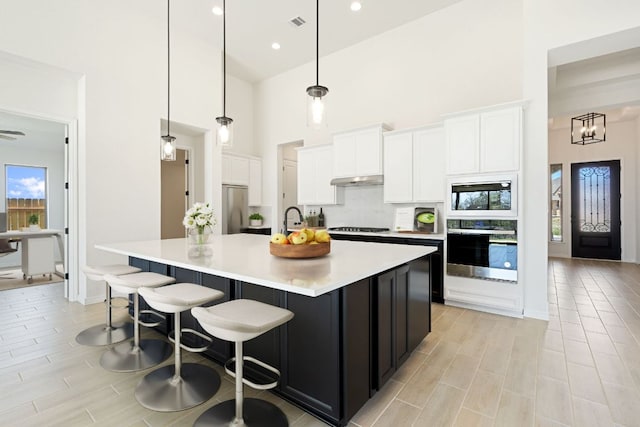 1832 Camay St, Leander, TX 78641 - kitchen featuring appliances with stainless steel finishes, a high ceiling, white cabinets, light countertops, and a large island