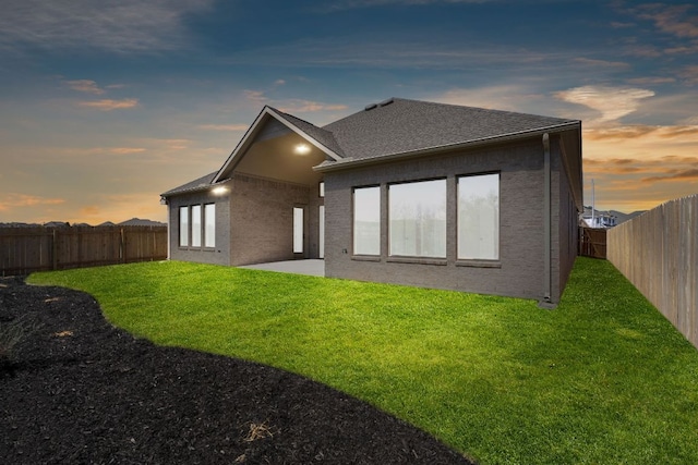 1832 Camay St, Leander, TX 78641 - back of property at dusk featuring a fenced backyard, a shingled roof, and a patio