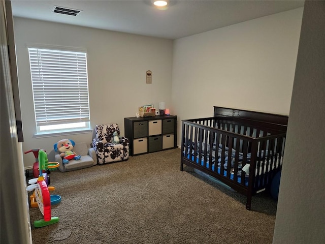 bedroom with a nursery area, carpet flooring, and visible vents