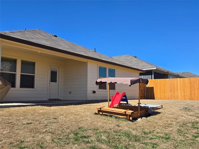 back of house featuring fence and a lawn