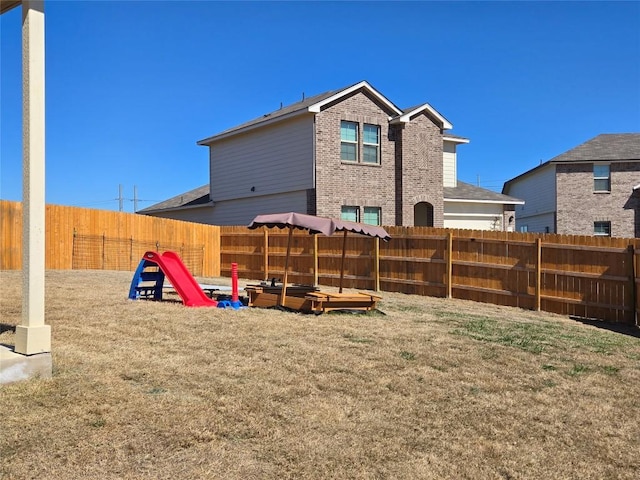 rear view of property featuring a yard, brick siding, and fence