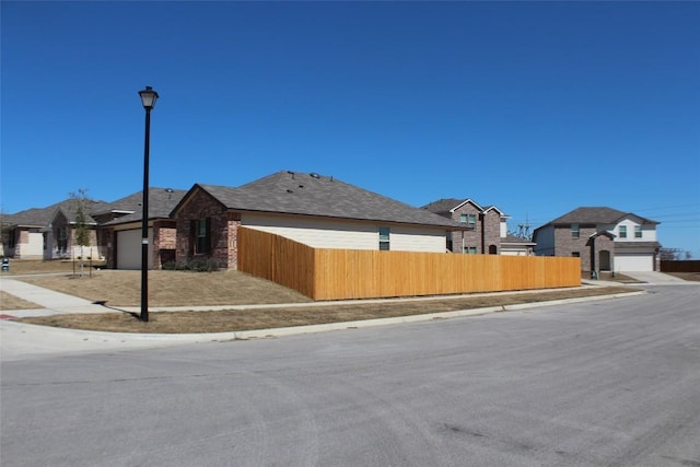 view of property exterior with a fenced front yard, brick siding, and a garage