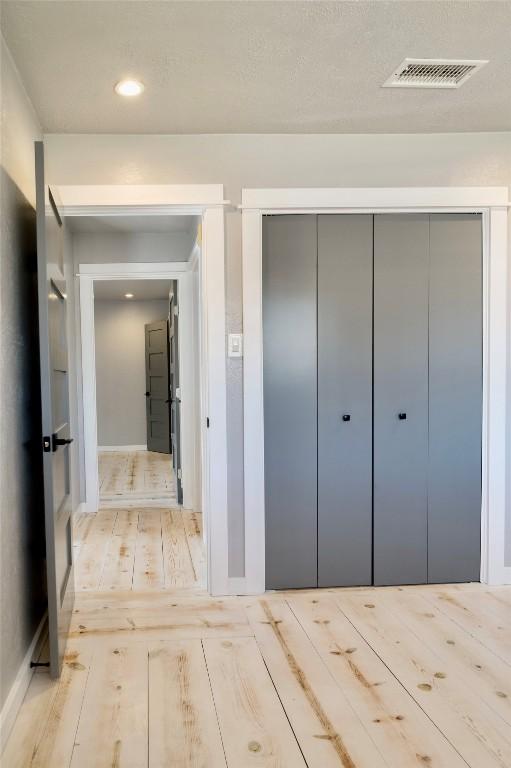 hallway featuring hardwood / wood-style floors, visible vents, and recessed lighting