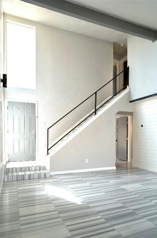 entryway with a towering ceiling, stairway, and beam ceiling