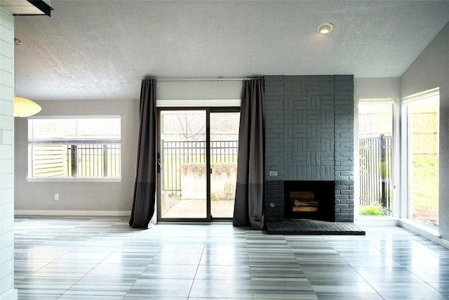 unfurnished living room featuring a textured ceiling, a fireplace, tile patterned flooring, and baseboards