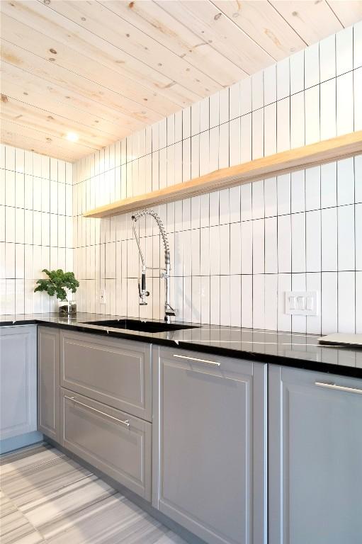 kitchen with dark countertops, a sink, backsplash, and open shelves