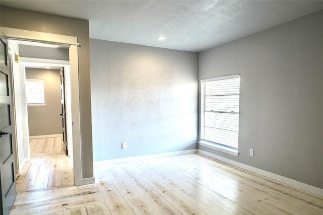 spare room with baseboards and hardwood / wood-style floors