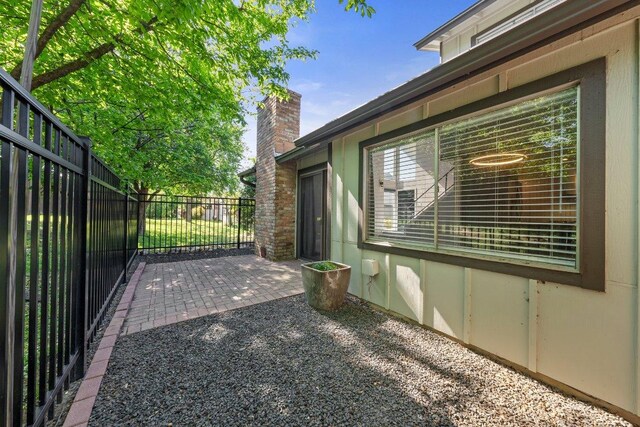 view of home's exterior with a chimney, a patio, and fence