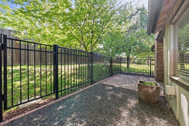 gate with a fenced backyard and a patio