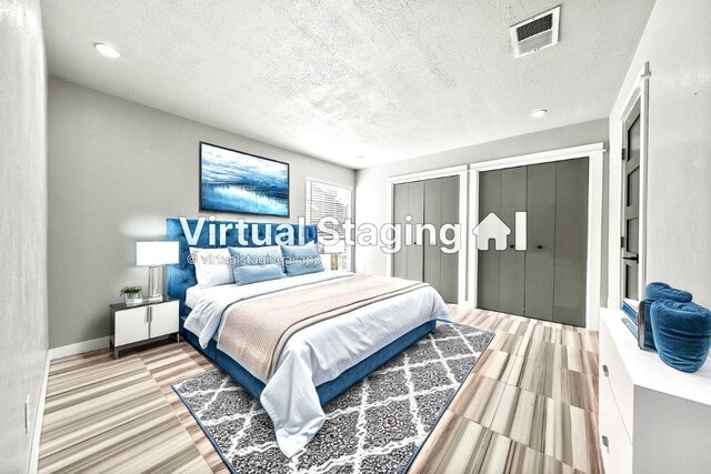 bedroom with two closets, a textured ceiling, and recessed lighting