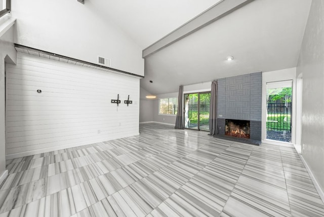 unfurnished living room with a fireplace, baseboards, and high vaulted ceiling