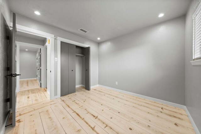 unfurnished bedroom featuring light wood-style floors, recessed lighting, baseboards, and a closet
