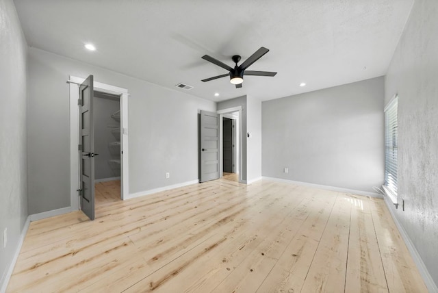 unfurnished bedroom featuring wood finished floors, a spacious closet, recessed lighting, ceiling fan, and baseboards