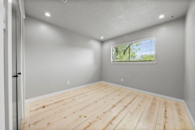 unfurnished room featuring recessed lighting, wood finished floors, and baseboards