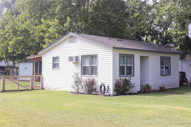 view of property exterior with a shingled roof, a yard, and fence