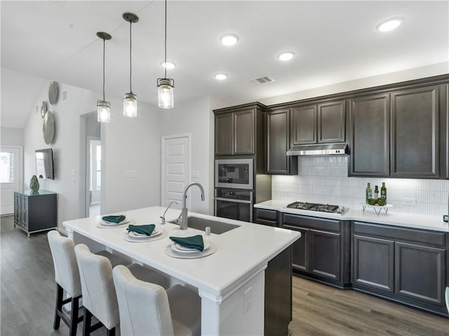 205 Bluff Creek Ln, Georgetown, TX 78628 - kitchen featuring appliances with stainless steel finishes, backsplash, dark wood-style flooring, light countertops, and dark brown cabinetry