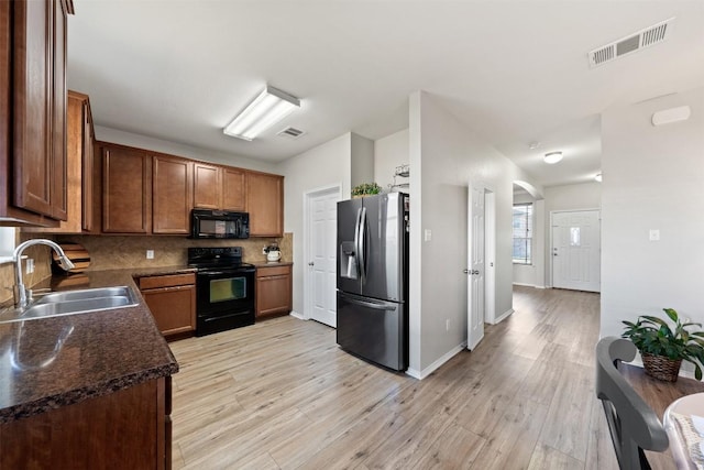 kitchen featuring tasteful backsplash, visible vents, a sink, and black appliances