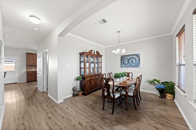 dining area featuring arched walkways, light wood-style flooring, visible vents, and baseboards