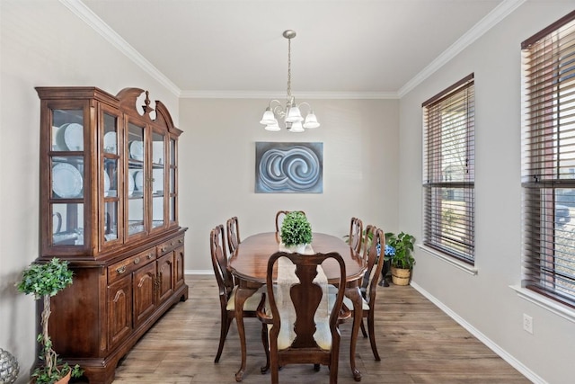 dining room with a chandelier, light wood-style floors, crown molding, and baseboards