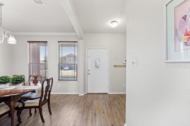 foyer featuring light wood-type flooring, visible vents, baseboards, and ornamental molding