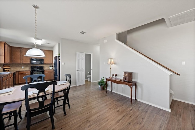 dining room featuring light wood-type flooring, baseboards, and visible vents