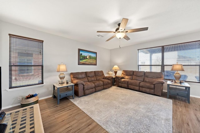 living area with a ceiling fan, wood finished floors, visible vents, and baseboards