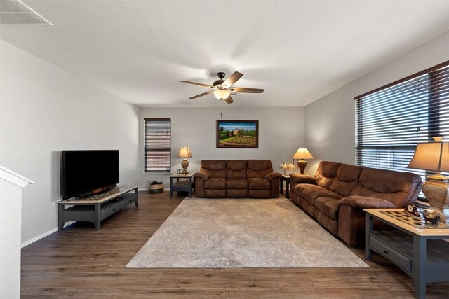 living room with a ceiling fan, visible vents, baseboards, and wood finished floors