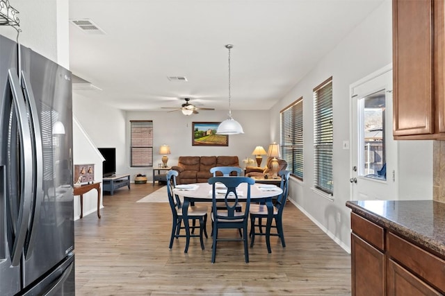 dining area with baseboards, light wood finished floors, visible vents, and a ceiling fan