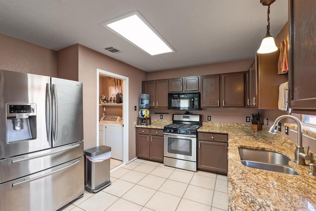 103 Ryan Cv, Hutto, TX 78634 - kitchen featuring stainless steel appliances, separate washer and dryer, light tile patterned flooring, light stone counters, and hanging light fixtures