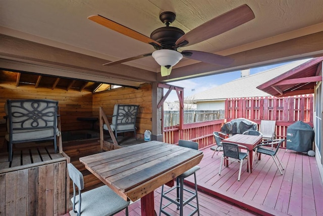 wooden terrace featuring ceiling fan, outdoor dining space, grilling area, and fence