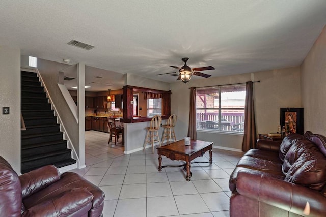 103 Ryan Cv, Hutto, TX 78634 - living room with stairway, light tile patterned flooring, and a ceiling fan