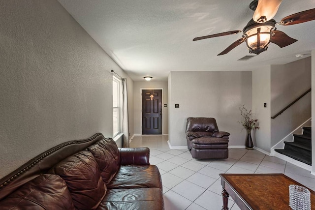 103 Ryan Cv, Hutto, TX 78634 - living area featuring a textured wall, stairs, light tile patterned floors, and a ceiling fan