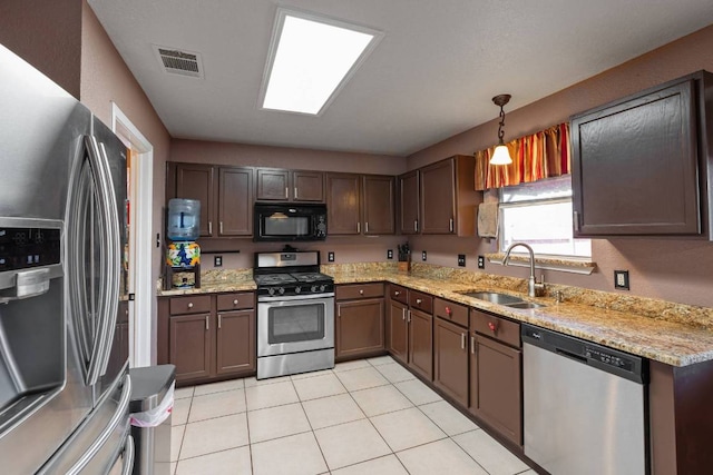 103 Ryan Cv, Hutto, TX 78634 - kitchen with appliances with stainless steel finishes, light tile patterned floors, light stone countertops, hanging light fixtures, and dark brown cabinets