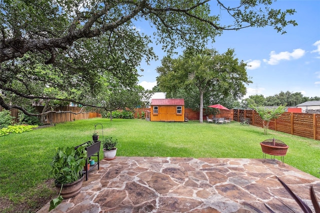 view of patio featuring an outdoor fire pit, a fenced backyard, an outbuilding, and a shed