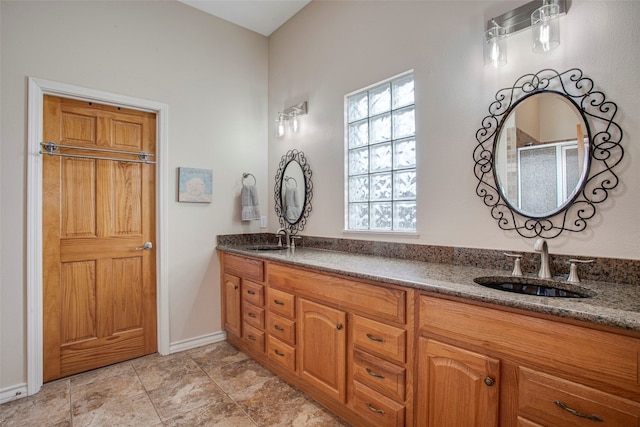 full bathroom featuring double vanity, baseboards, a sink, and a shower with shower door