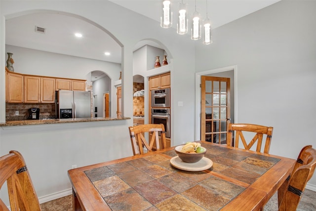 dining space featuring baseboards, visible vents, arched walkways, and built in features