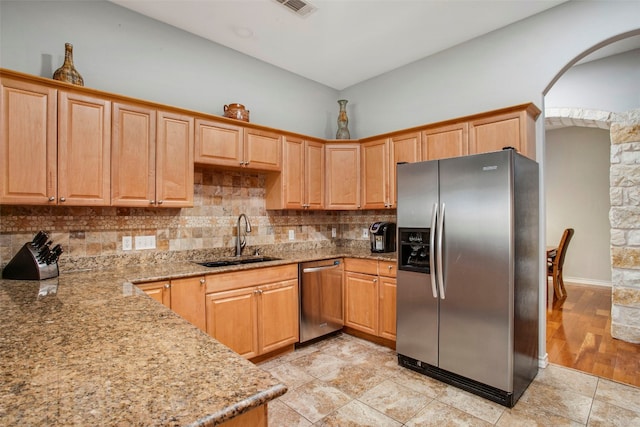 kitchen with a sink, visible vents, appliances with stainless steel finishes, backsplash, and light stone countertops