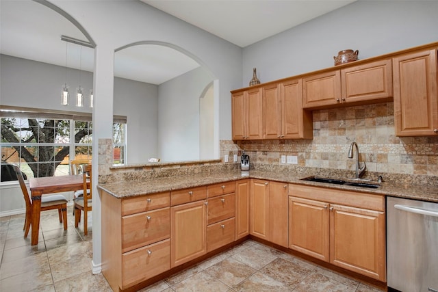 kitchen featuring light stone counters, decorative light fixtures, backsplash, stainless steel dishwasher, and a sink