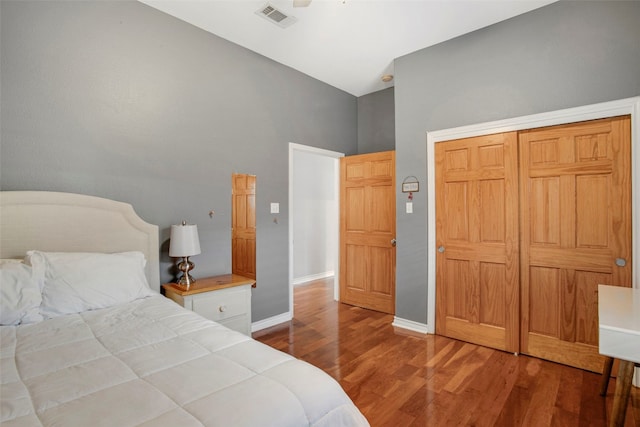 bedroom with baseboards, visible vents, and wood finished floors