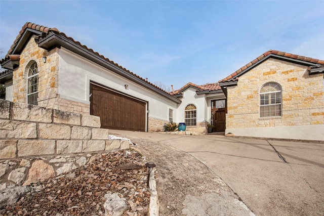 view of front of house with driveway, an attached garage, a tile roof, and stucco siding