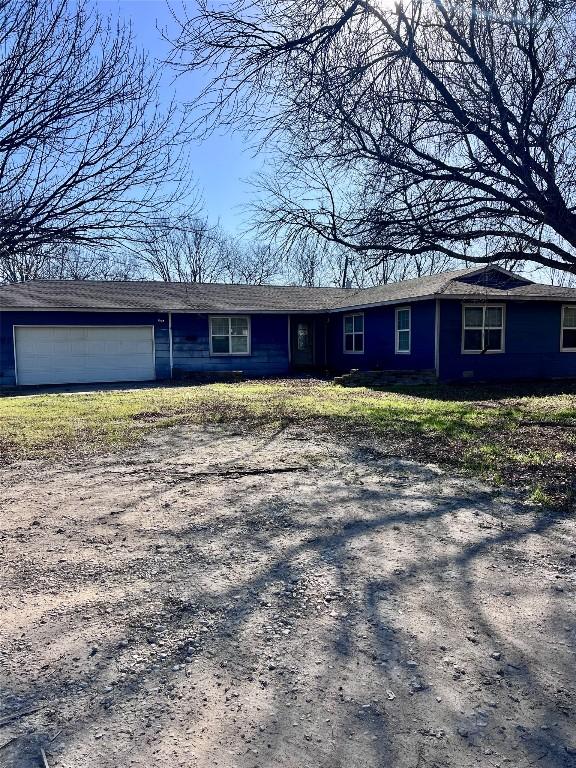 single story home with dirt driveway and an attached garage