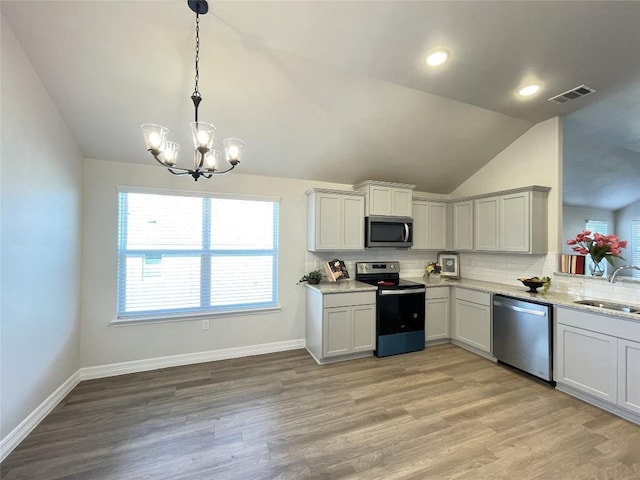 kitchen featuring appliances with stainless steel finishes, vaulted ceiling, a sink, and tasteful backsplash