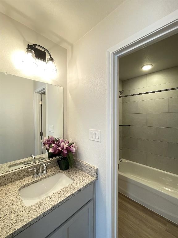 bathroom featuring shower / bathing tub combination, wood finished floors, and vanity