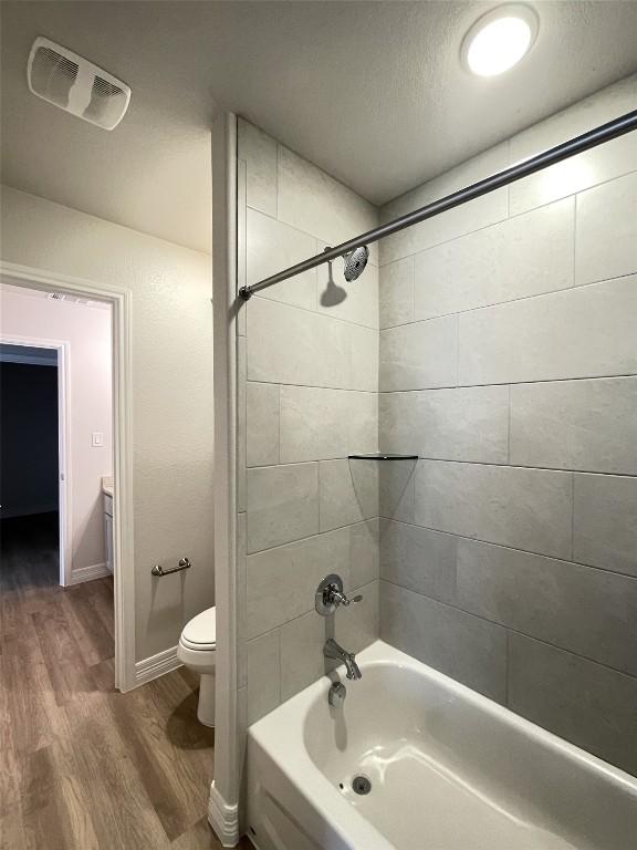 full bathroom featuring baseboards, visible vents, toilet, shower / tub combination, and wood finished floors